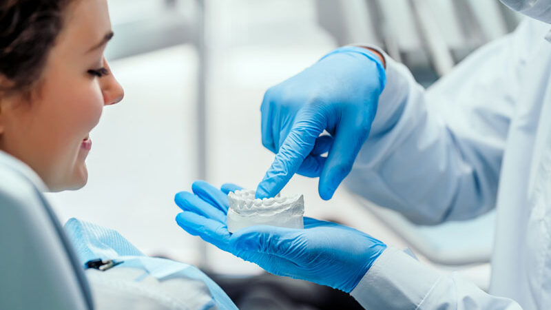 a dentist showing an implant patient a dental implant model.